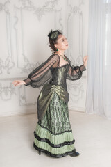 Beautiful young smiling woman wearing green medieval vintage Victorian Style dress turn