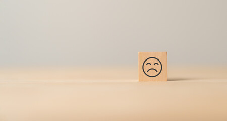 Unhappy face emoticon on wooden cube blocks.Customer dissatisfaction experience. Bad experience,...