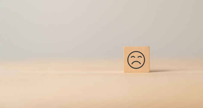Unhappy face emoticon on wooden cube blocks.Customer dissatisfaction experience. Bad experience, bad review, bad service, dislike, bad quality, low rating. Service rating, satisfaction concept.