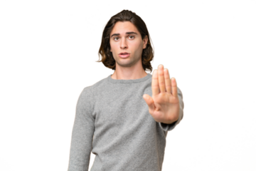 Young caucasian man isolated on green chroma background making stop gesture