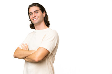 Young caucasian man isolated on green chroma background with arms crossed and happy