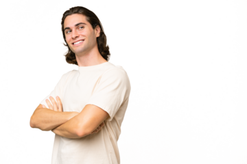 Young caucasian man isolated on green chroma background with arms crossed and happy