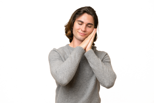 Young caucasian man isolated on green chroma background making sleep gesture in dorable expression