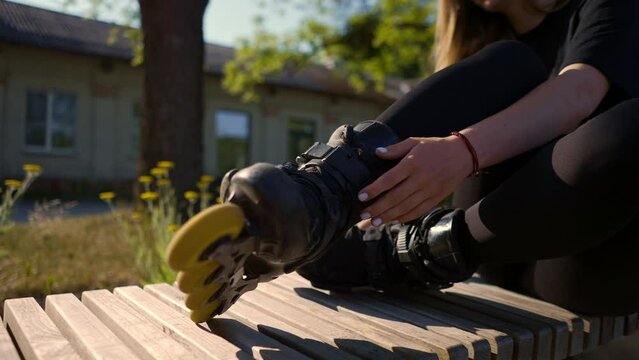young beautiful girl in park tying laces on roller skates before skating workout active lifestyle hobby