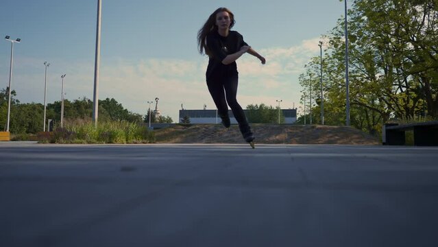 sporty girl rides roller skates in park on city background Active girl in enjoys roller skating lesson on street Street sports concept