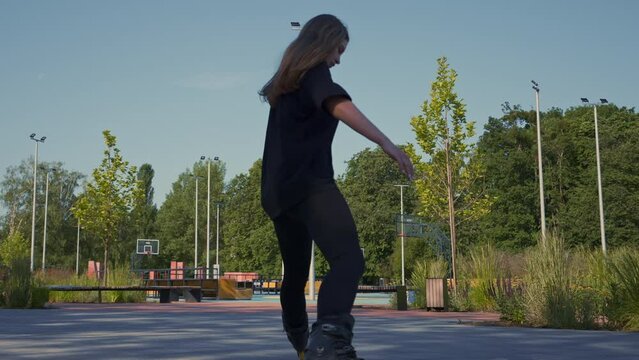 sporty girl rides roller skates in park on city background Active girl in enjoys roller skating lesson on street Street sports concept
