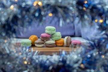Close up delicious macaroon cookies in fresh mint green vanilla beige chocolate brown orange and pink colors. Blue bokeh shining blurred foreground decor. Contrast bright combination, bakery culinary.