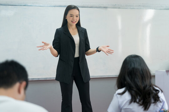 Female teacher giving lecture and explaining lesson to the college students in classroom