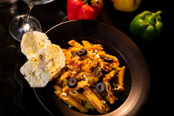 Pasta  decorated with cut Olives on a wooden table. Traditional Italian food with Red green Capsicum on table
