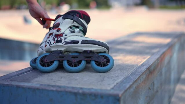 close-up hand takes roller skates to frame in skate park outdoor training skating extreme sport