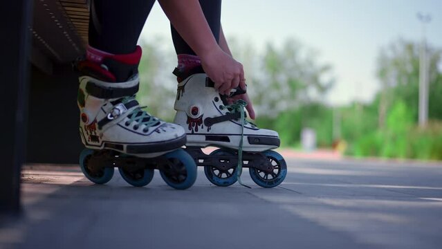 young hipster girl wearing roller skates tying laces in skate park before skating street extreme sport close-up of legs