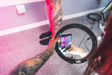 Tattoo artist using ring light to take a photo of her client's new leg tattoo. Tattooist taking photo of tattoo on calf of client. High quality photo
