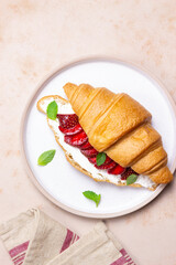 Croissant with strawberries, white cheese and mint. Breakfast. Vegetarian food.