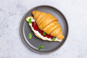 Croissant with strawberries, white cheese and mint. Breakfast. Vegetarian food.
