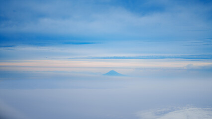 Fototapeta na wymiar 飛行機の窓から見える山と雲の風景