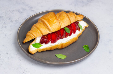 Croissant with strawberries, white cheese and mint. Breakfast. Vegetarian food.