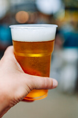plastic cup glass with beer in hand. Outdoor summer festival