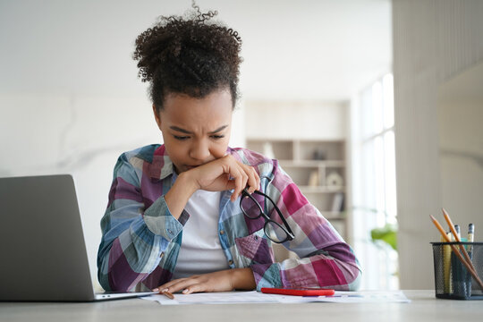 Pensive Biracial Student Diligently Prepares For Exams, Studying At Home Desk. Tired Yet Focused, Engaged In Distance Education.