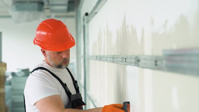 A uniformed worker applies plaster to the drywall wall. Putty of joints of drywall sheets