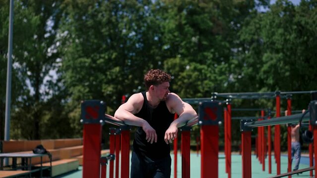 portrait of a young sweaty sportsman after an outdoor workout on a horizontal bar or parallel bars