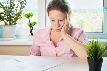Shocked expression of a young woman as she looks at bills and fees in bank documents, employee...