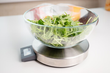 diet and weight loss, calorie counting, salad in a bowl on a digital kitchen scales