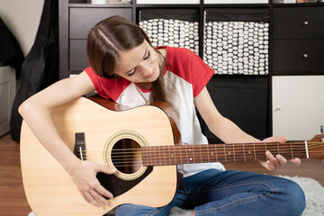 teenager girl playing guitar at home in teen room, young guitarist practicing diligently, honing her skills