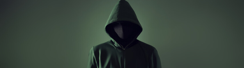An anonymous hacker in a green hoodie on a green background. Cyber pirate face hidden isolated...