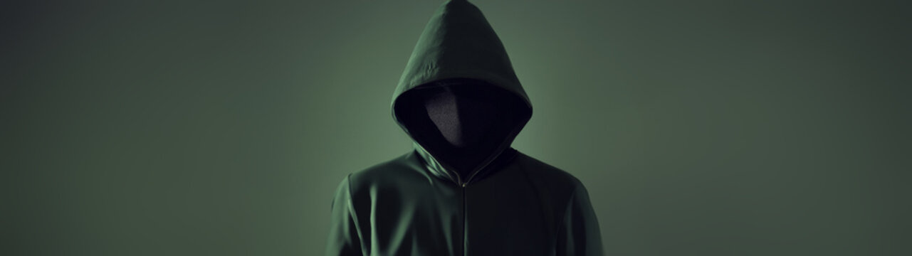 An anonymous hacker in a green hoodie on a green background. Cyber pirate face hidden isolated studio front plan, space for text.
