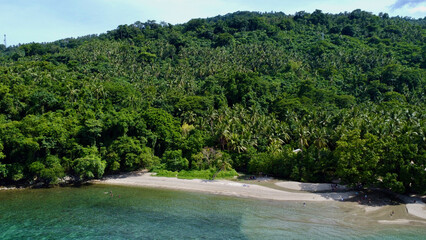 Fototapeta na wymiar Aerial view of a tropical island. Blue sea, sandy beach, jungle and white clouds over the horizon.