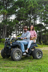 Portrait of young married couple sitting on a quad bike in the forest
