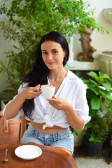 Portrait of smiling ukrainian woman drinking hot capuccino and looking at camera