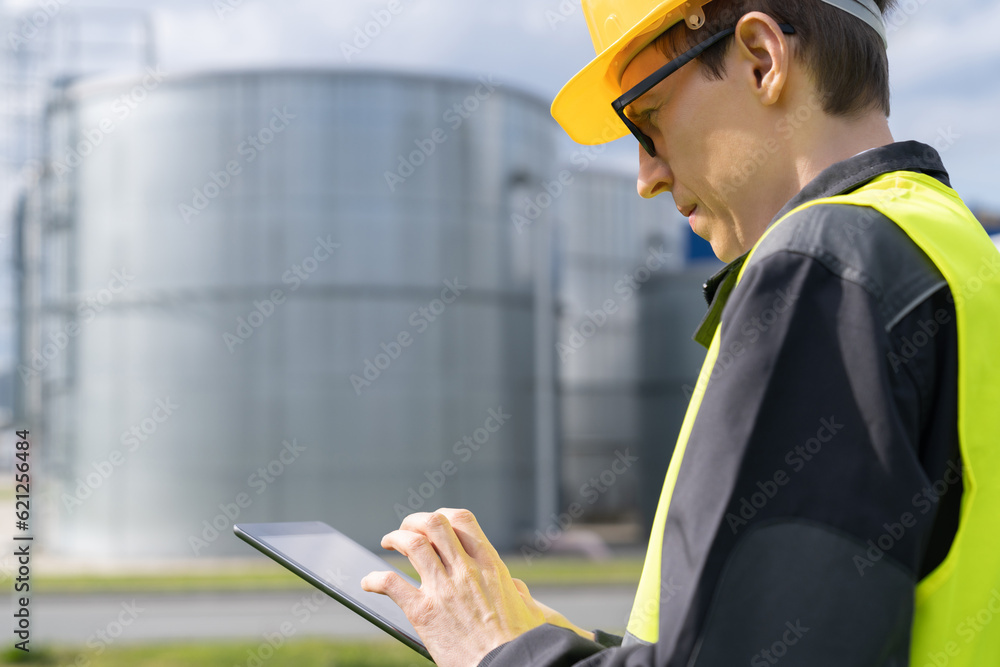 Poster Engineer with digital tablet on a background of gas tanks.