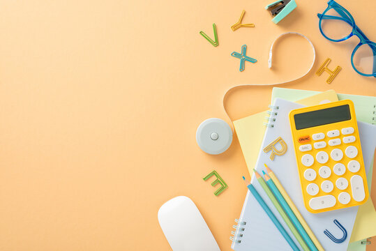 Study essentials laid out on pastel orange backdrop with space for text. Top view of stationery, copybooks, pencils, calculator, spectacles, tape, computer mouse, creating perfect back-to-school scene