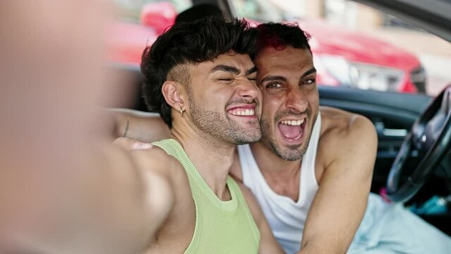 Two men couple make selfie by smartphone sitting on car at street