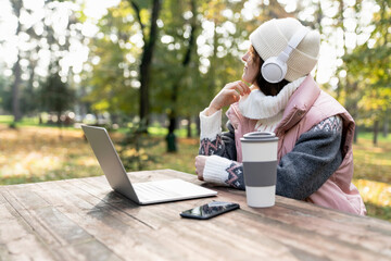 Freelancer working on laptop in autumn park.