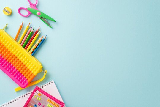 Immerse yourself in world of education for small kids with top view composition: lively collection of colorful school supplies on pastel blue surface, providing copyspace for text or advertisements