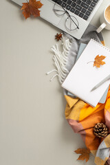 Autumnal office setup. Vertical top view laptop, diaries, spectacles, comfy scarf, yellowish maple leaves, pine cone, coffee cup, anise placed on light grey backdrop with blank space for text or ad