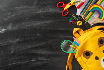 Explore the wonders of early education with this top-down perspective of arrangement of child stationery and cute school bag on blackboard backdrop, offering copyspace for text or advertising content © ActionGP