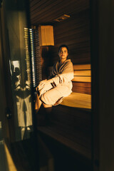 Tanned young woman is sitting in sauna.