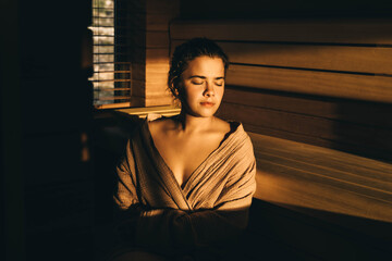 Tanned young woman is sitting in sauna.