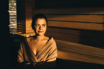 Tanned young woman is sitting in sauna.