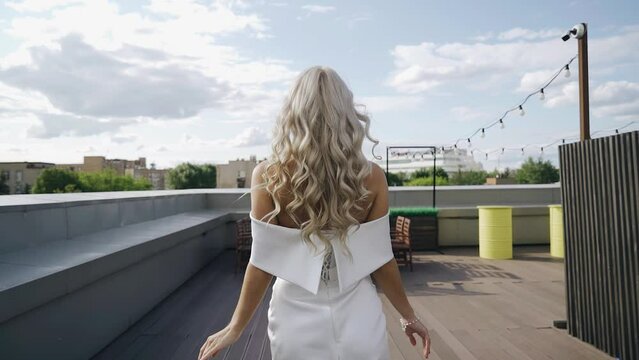 The girl walks on the roof and turns around sharply, spinning around herself. Her hair is moving in the wind. Cool shots in slow motion
