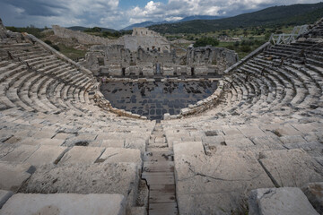 Roman theater at archaeological site of ancient city Patara in Lycia under cloudy sky, Turkey