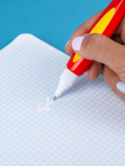A hand holds a black corrective pencil to remove excess tape information on the table.