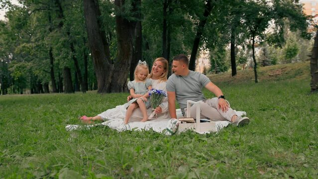 happy family rests in nature in the park celebrate the birthday of the little ones a bouquet of flowers hugs the child