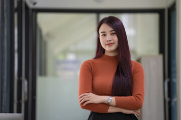 Beautiful Asian businesswoman standing with her arms crossed and looking at the camera.