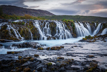 Scenic image of Iceland. Incredible nature landscape. Stunning view of Bruarfoss Waterfall. Azure water flows over stones. Bright midnight sun of Iceland. Iceland is a most popular place of travel.