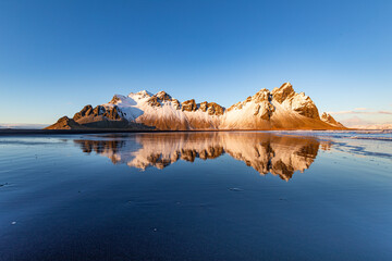 The incredible landscape of Vestrahorn in the south of Iceland. Beautiful back reflecting the...
