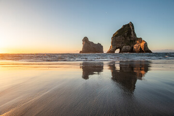 Wharariki beach famous from a background wallpaper during sunset with a wonderful reflection in the...